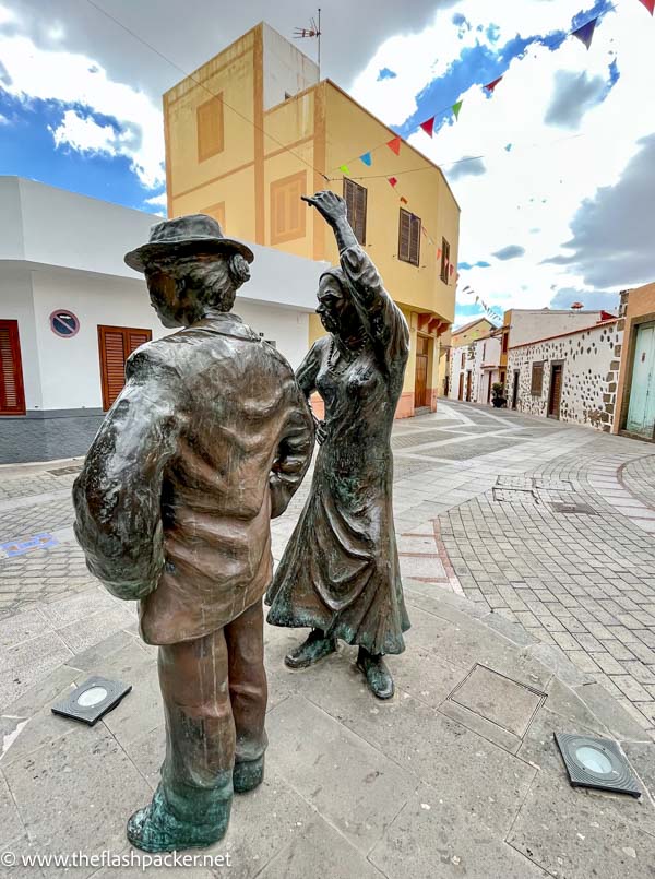 bronze sculpture of 2 people dancing in a colonial town