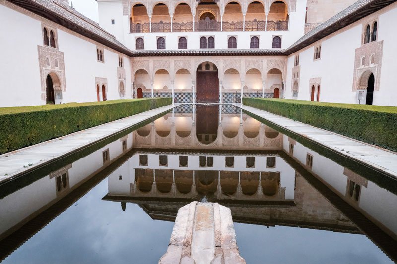 islamic courtyard with horseshoe arches and central reflecting pond