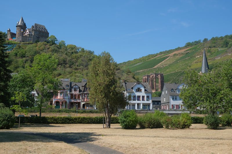 view of the town of bacharach in germany with a ruined chapel, medieval houses and a castle on the hill