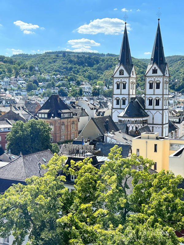 twin black and whiote bell towers of an old church amongst the old buildings of the town of boppard in germany