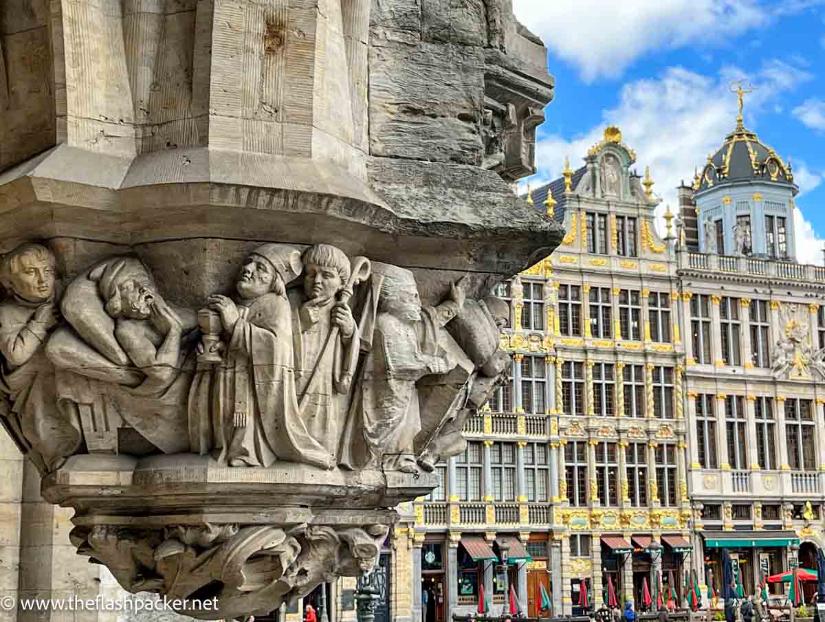 detailed sculpture of figures on a pillar with gable roof buildings in background