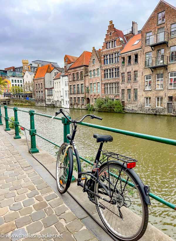 bicycle chained alongside a pretty canal in ghent belgium