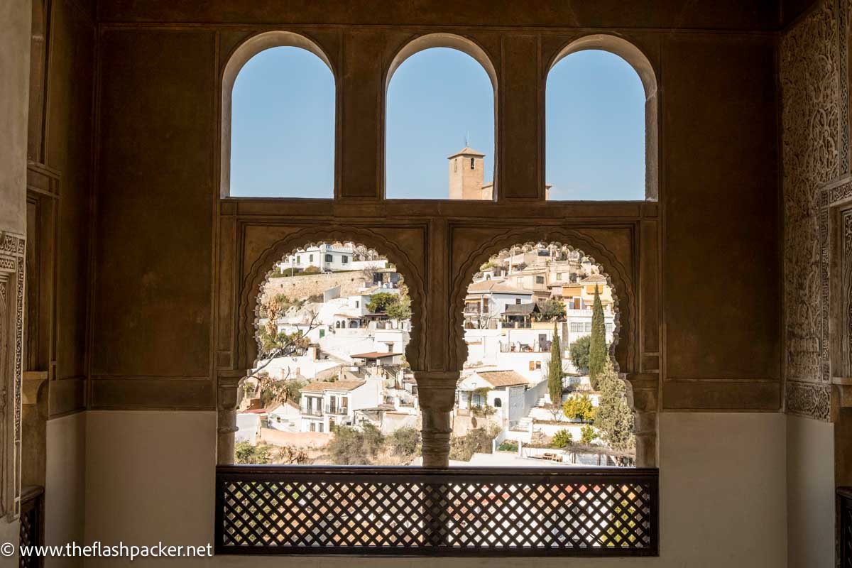 view of the white buildings of granada spain through arched windows