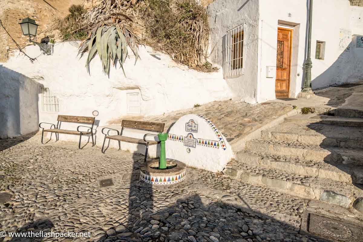 small open plaza with2 benches and whitewashed buildings