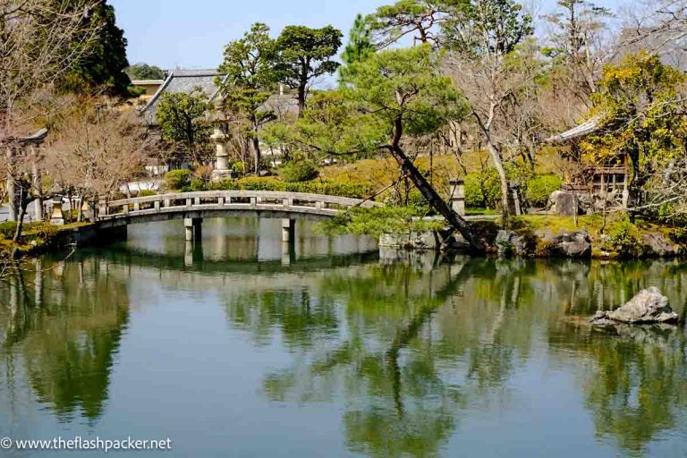 stone bridge crossing lake with reflections at eikando in kyoto japan