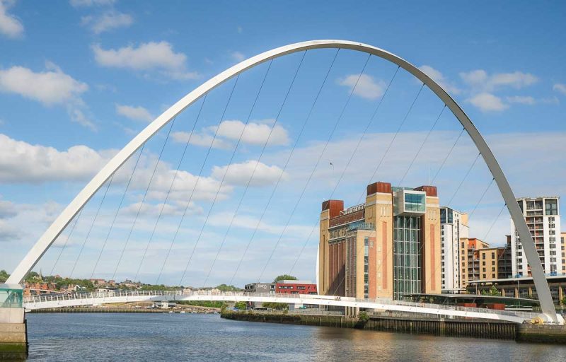 curved arch of newcastles milennium bridge and buildings along the riverfront