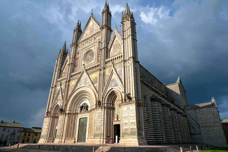 gothic facade of orvieto cathedral under a stormy sky