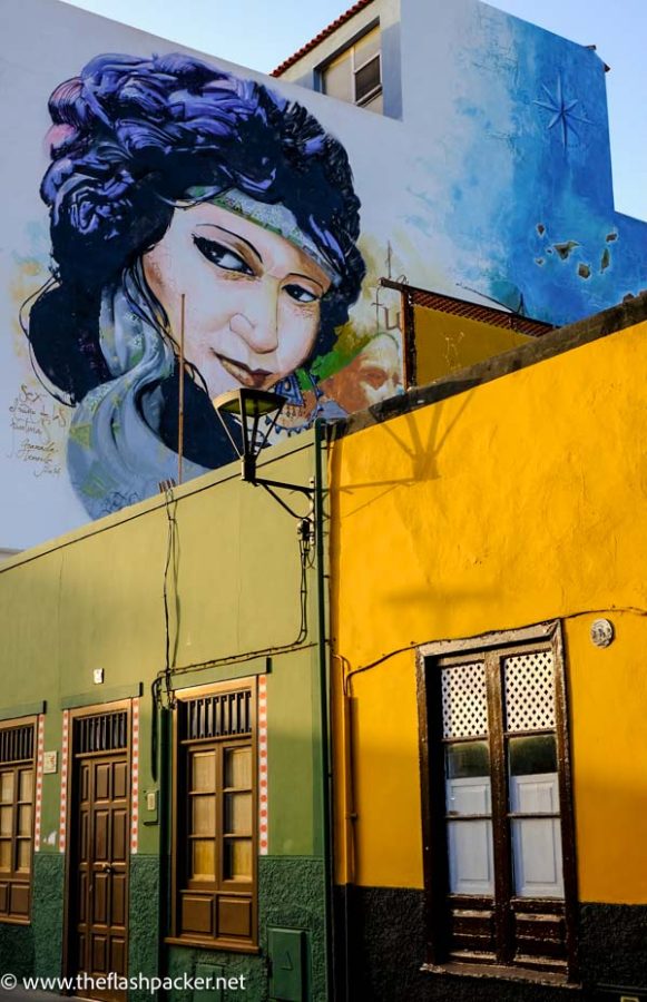 ochre coloured buildings and mural of womans face