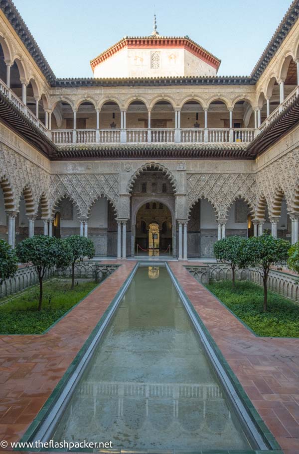 reflective pond in the centre of an ornate Moorish courtyard seen when visiting the real alcazar of seville