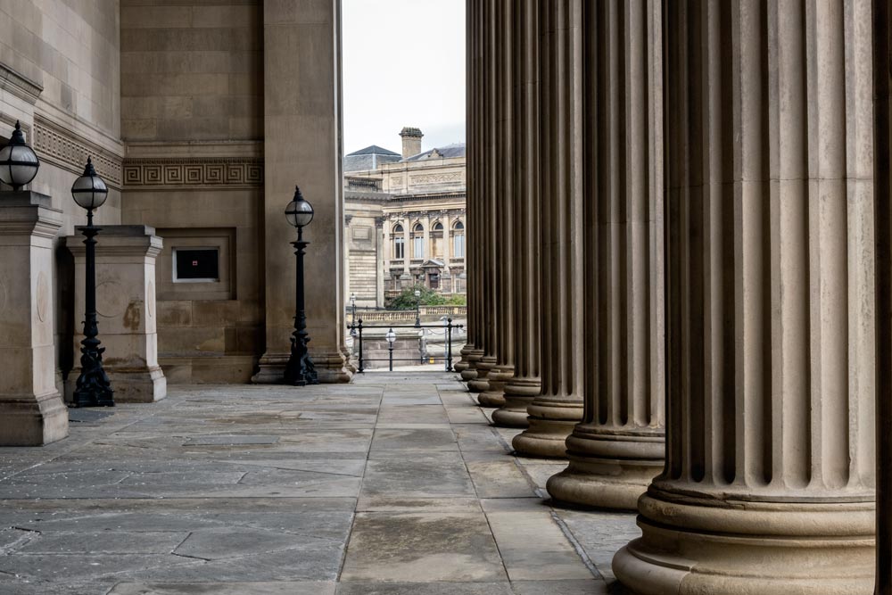 row of corinthian columns on a buildings portico with neoclassical building in distance