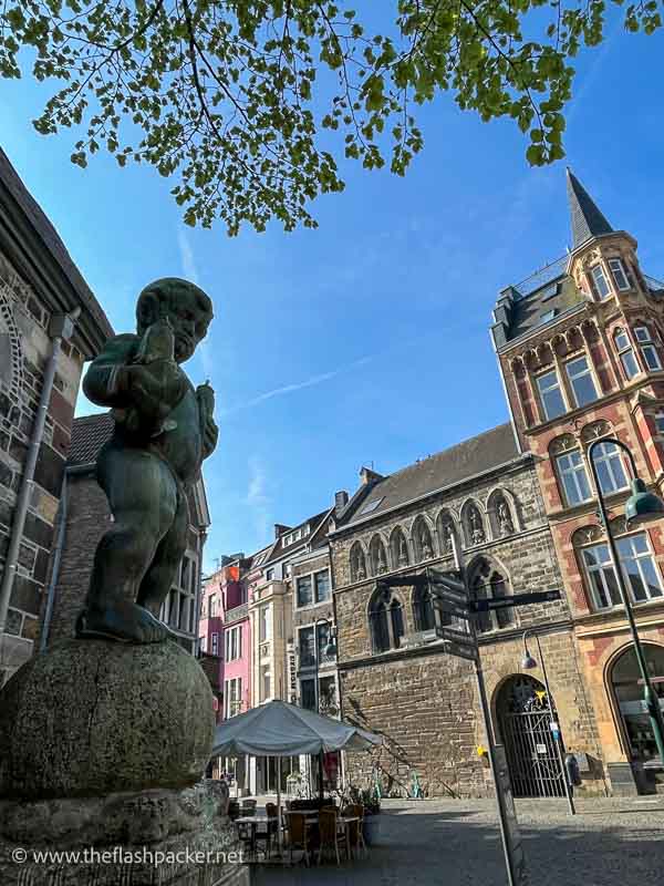 sculpture of naked boy holding two fish in a square in aachen germany