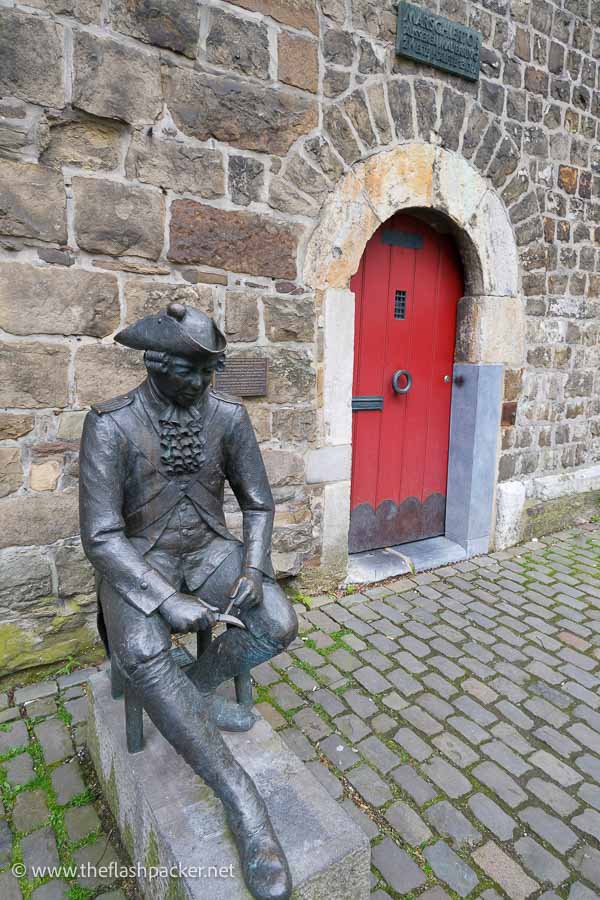 bronze sculpture of soldier next to brick building with a red door