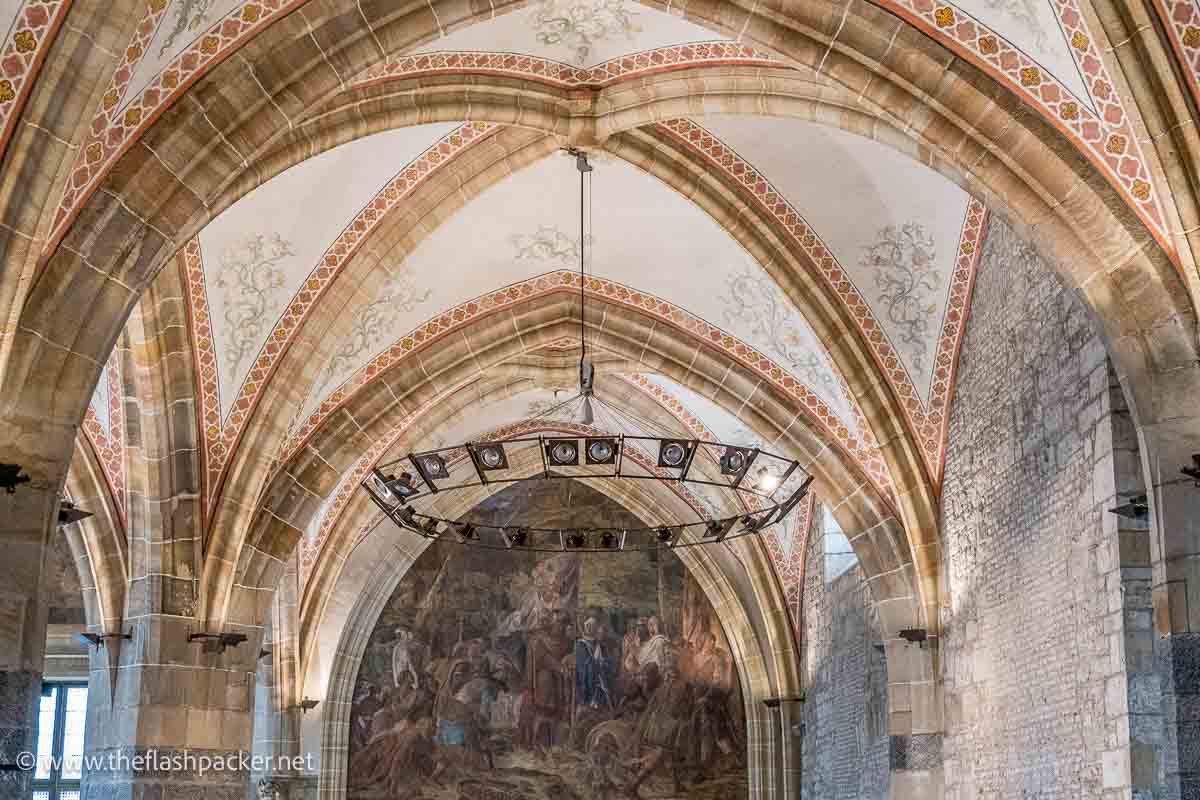 grand hall with a vaulted ribbed ceiling and large painting on wall