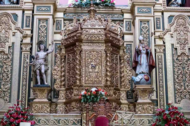 ornate gilded tabernacle in church with a small statue on either side