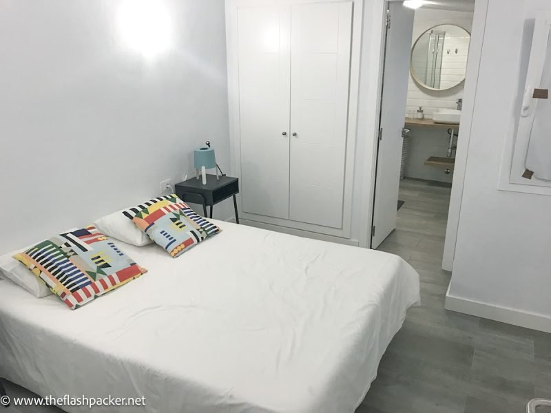 bed with white bedding and brightly coloured cushions