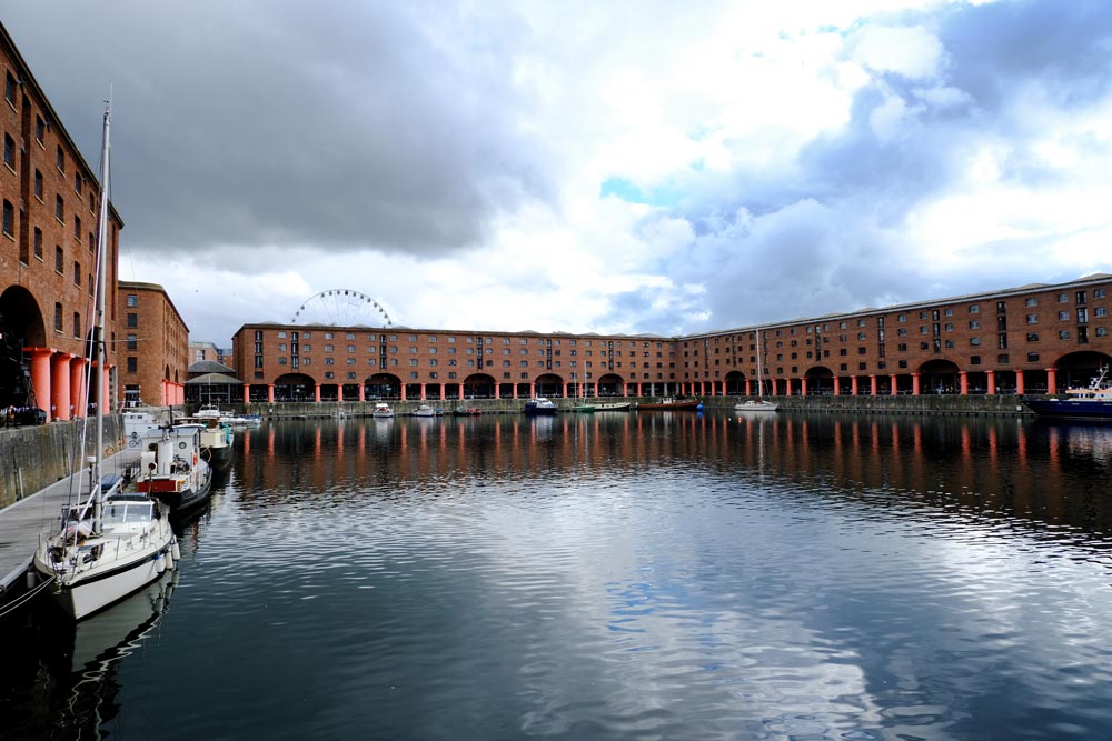 rows of red brick warehouse buildings reflected in the water of a dock