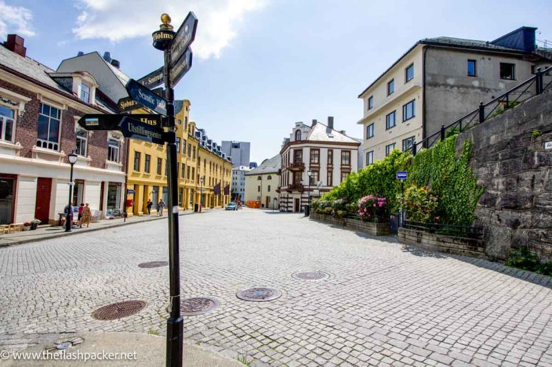 cobbled street with signpost and pastel colored buildings