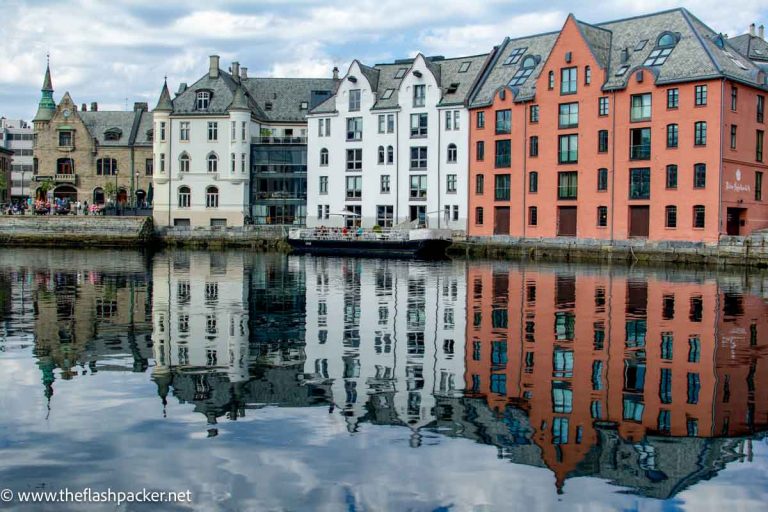 brightly colored buildings reflected in water of harbour in the art nouveau town of alesund norway