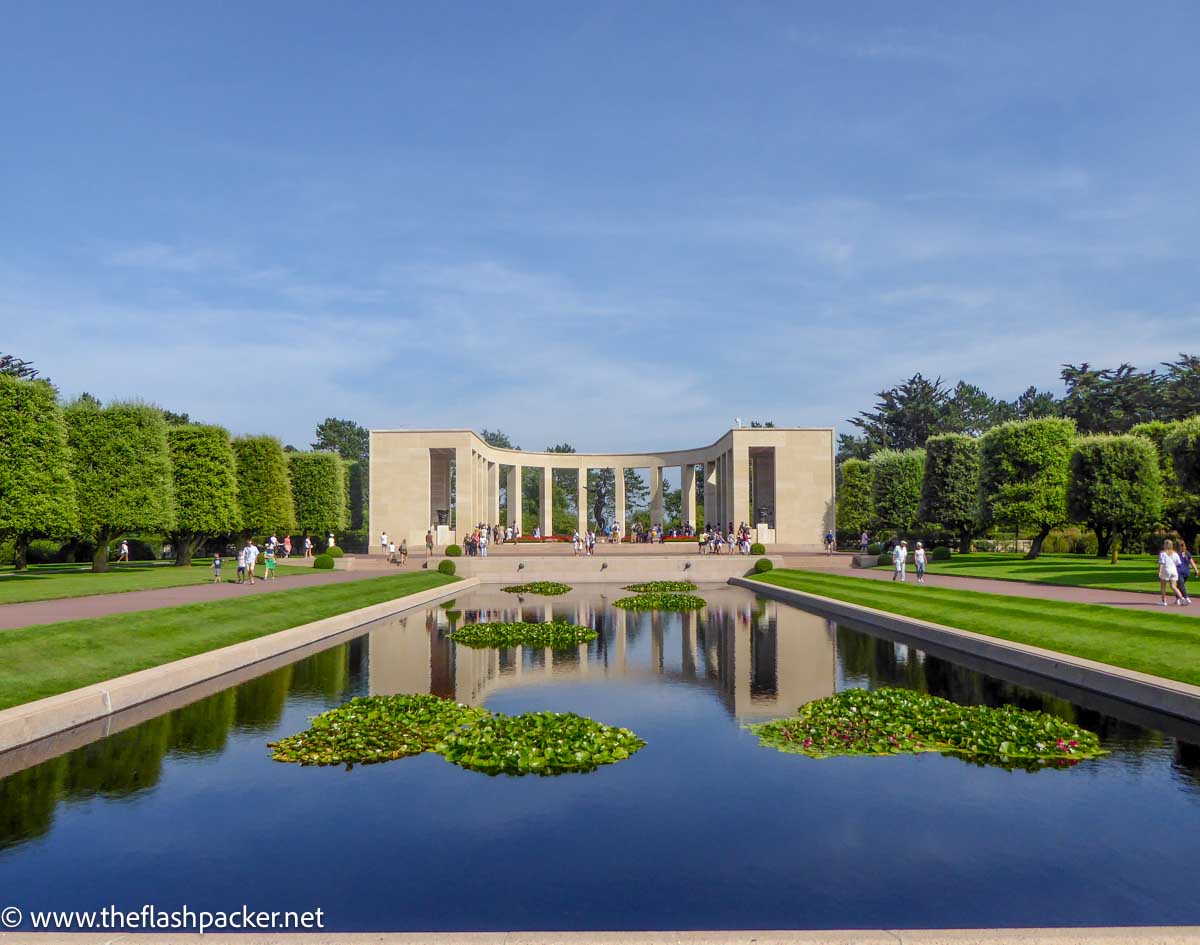 rectangular pond in front of semi-circular stone memorial at the american war cemetery at omaha beach in normandy