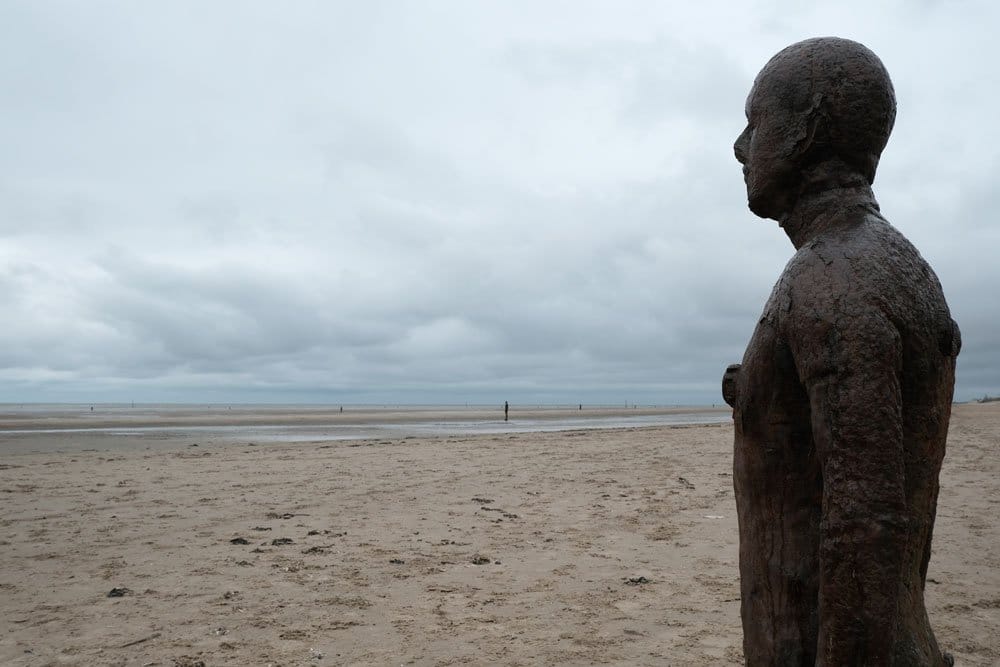 large statue of man on a sandy beach