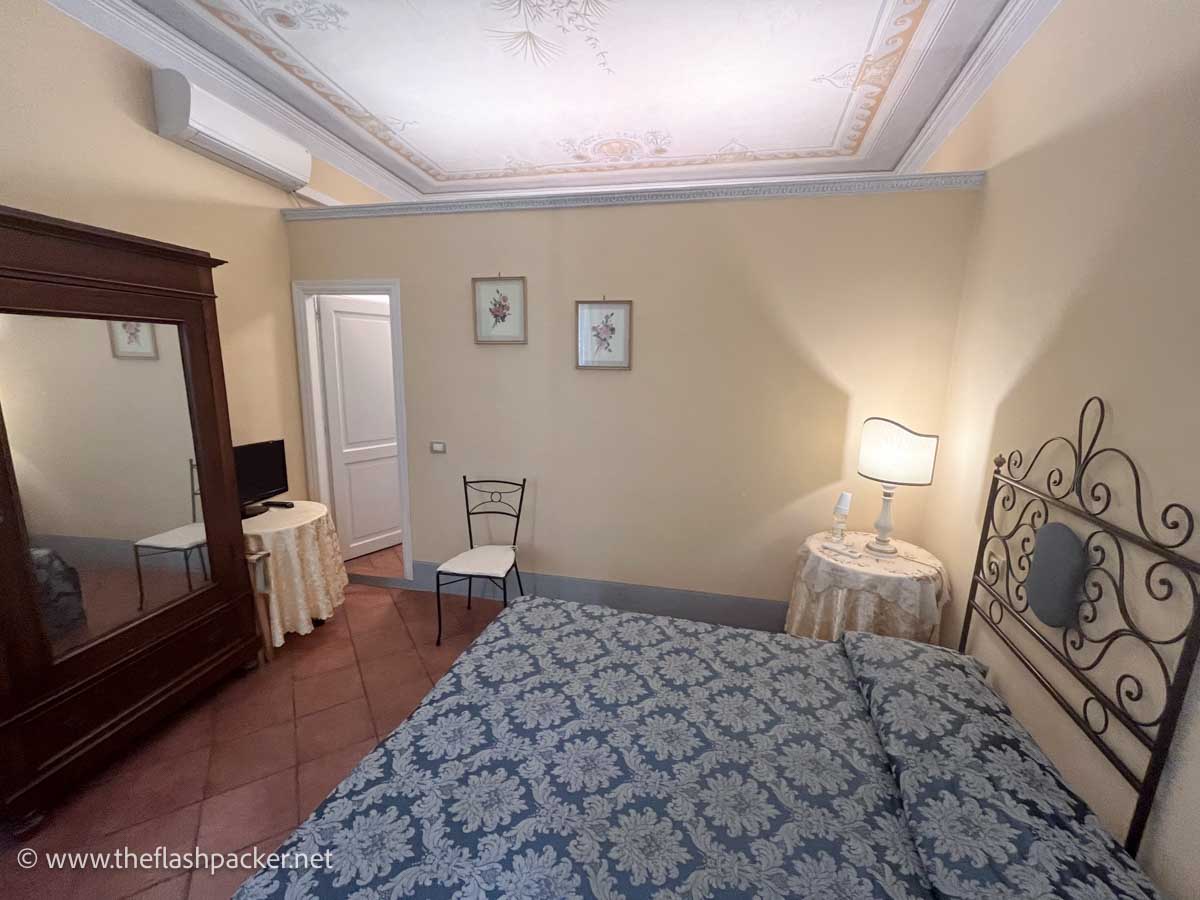 simple room in antica residenza cicogna guesthouse in siena with large bed, tiled floor and frescoed ceiling