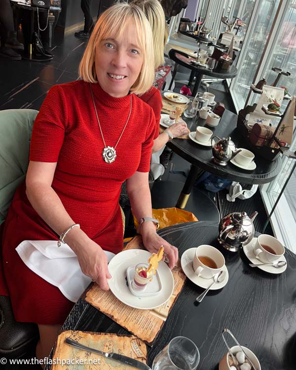 blonde woman sitting at a table with tea and cake in the shard london