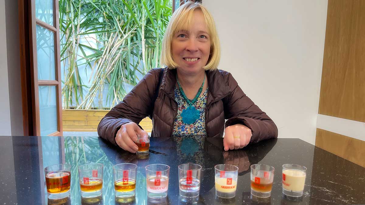 woman sitting behind a line of glasses with rum tastings