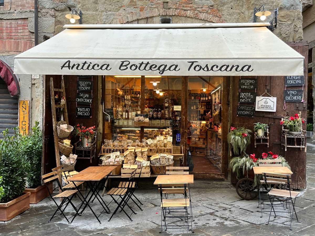 food shop in a city in tuscany in italy with tables and chairs outsdie