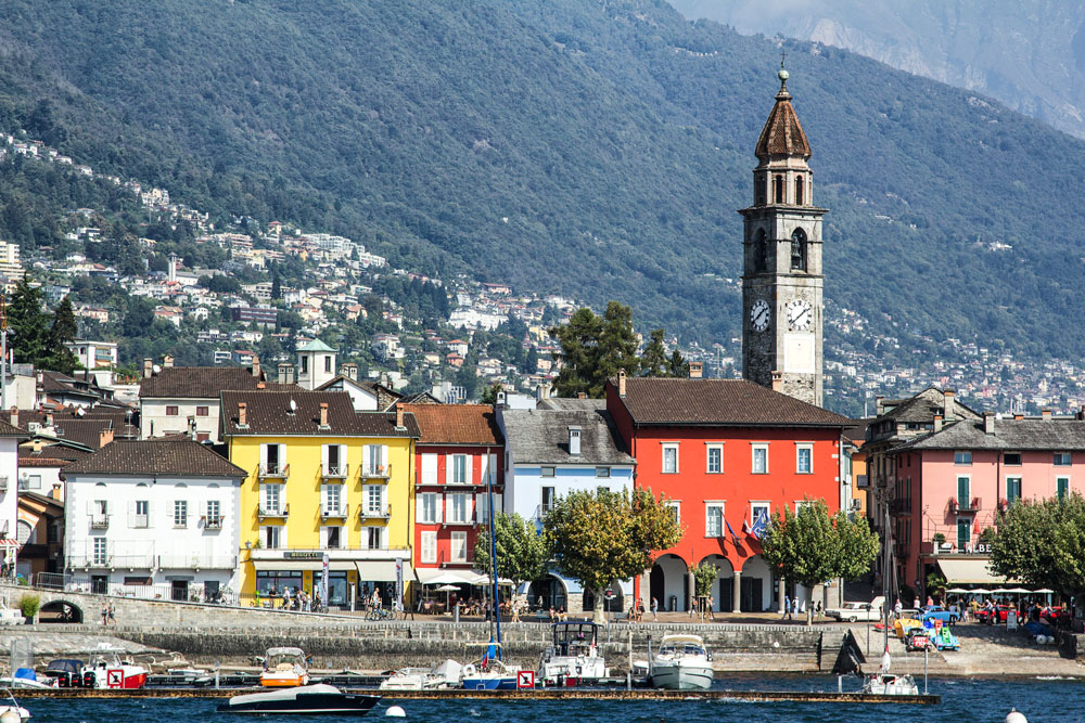 brightly coloured buildings and church along the shore at ascona