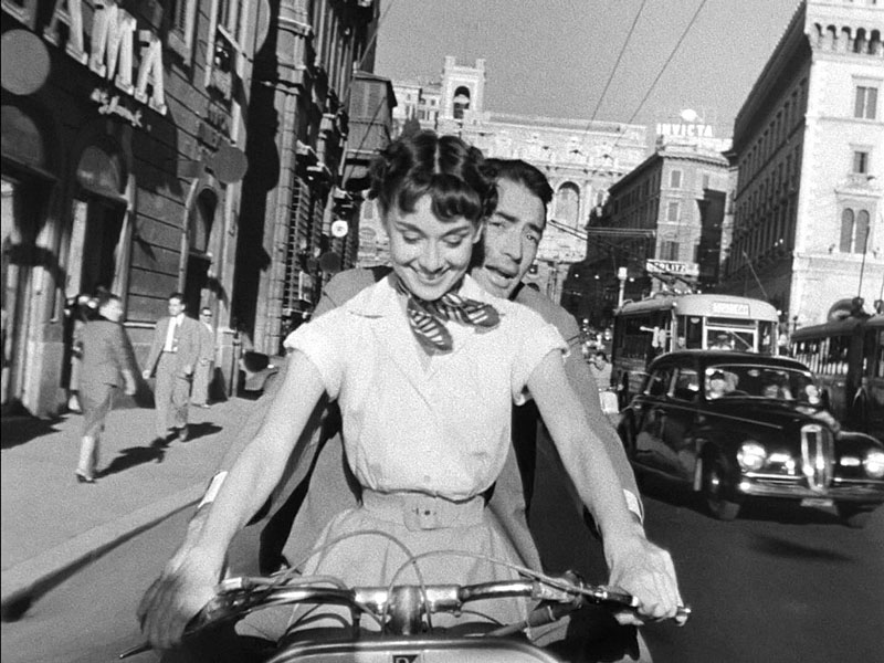 Audrey_Hepburn_and_Gregory_Peck_on_Vespa_in_Roman_Holiday