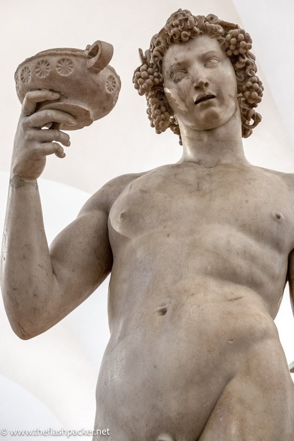 statue of the god bacchus raising a cup to his lips