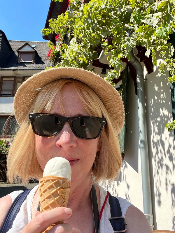 blonde woman wearing sunhat eating an icecream