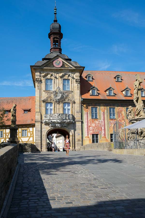 woman walking across bridge leading to medieval building with a tower