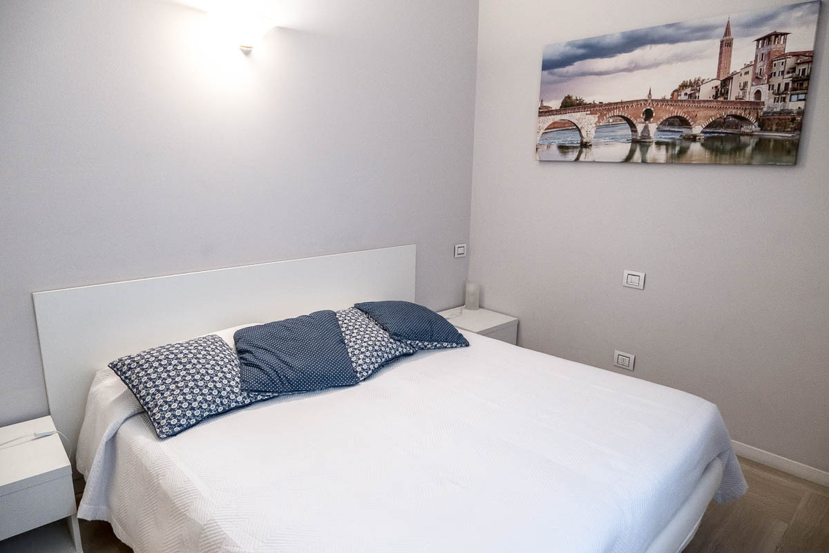 double bed with white linen and blue cushions at b&b valverde in verona