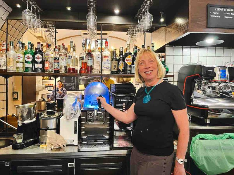 blond woman standing in front of an italian bar counter