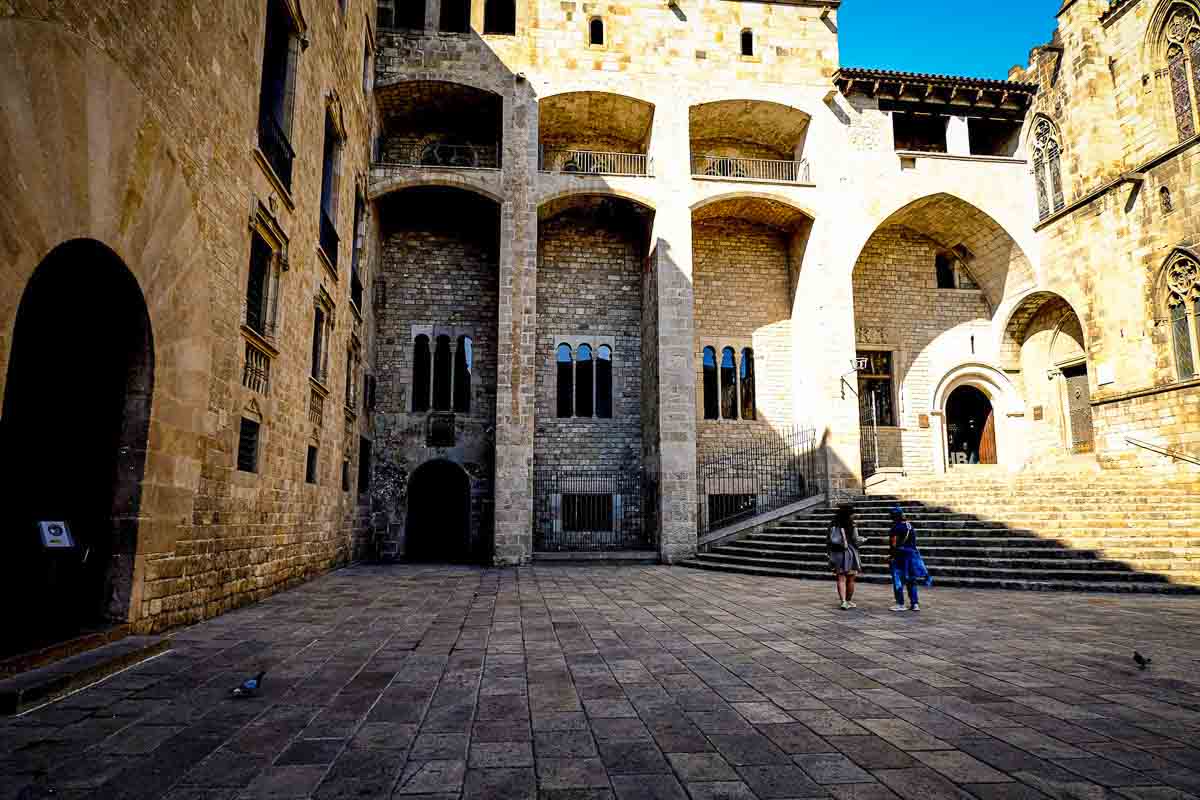 shaded plaza surrounded by medieval stone buildings