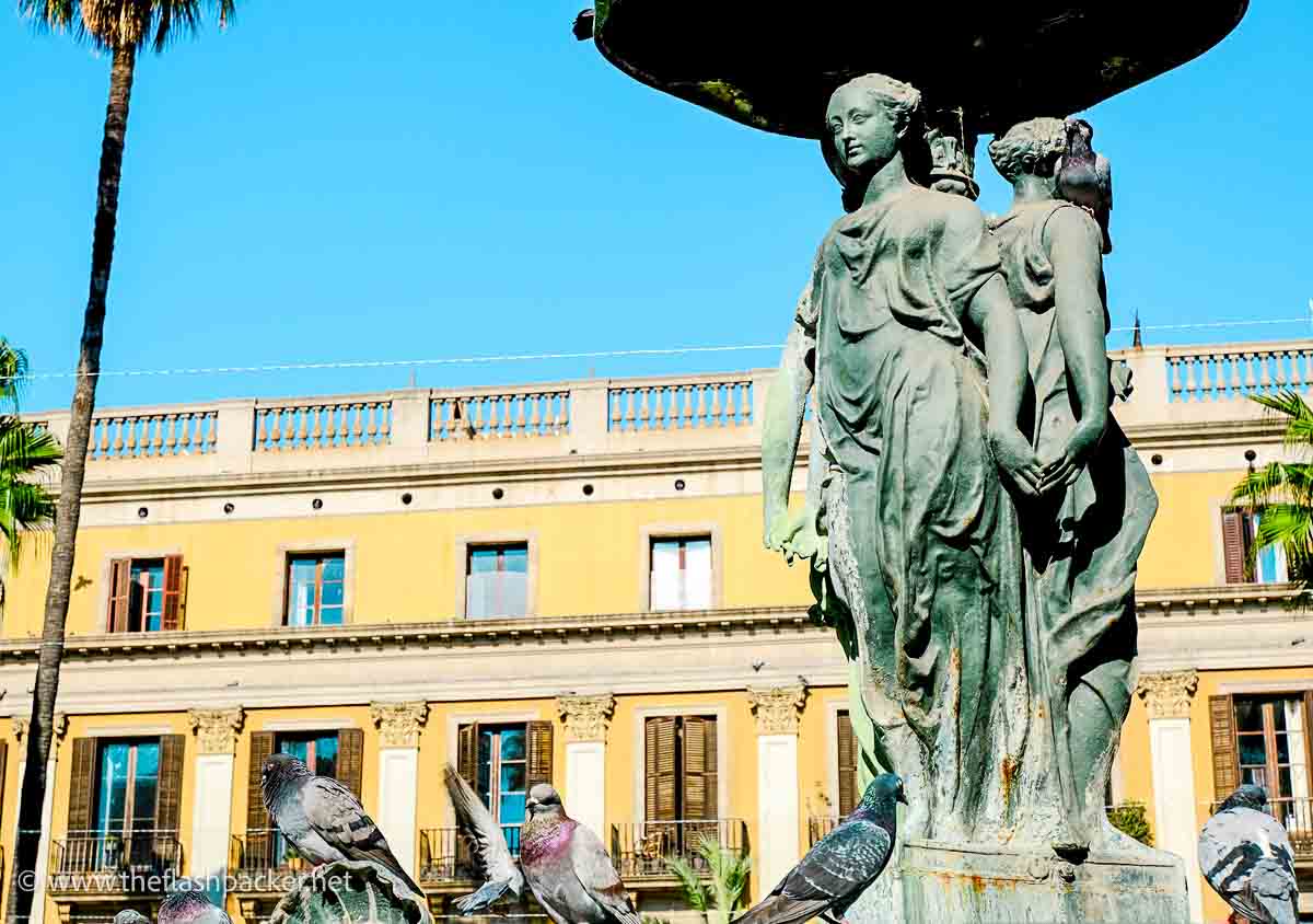 classical staues of draped women in front of ochre colored building