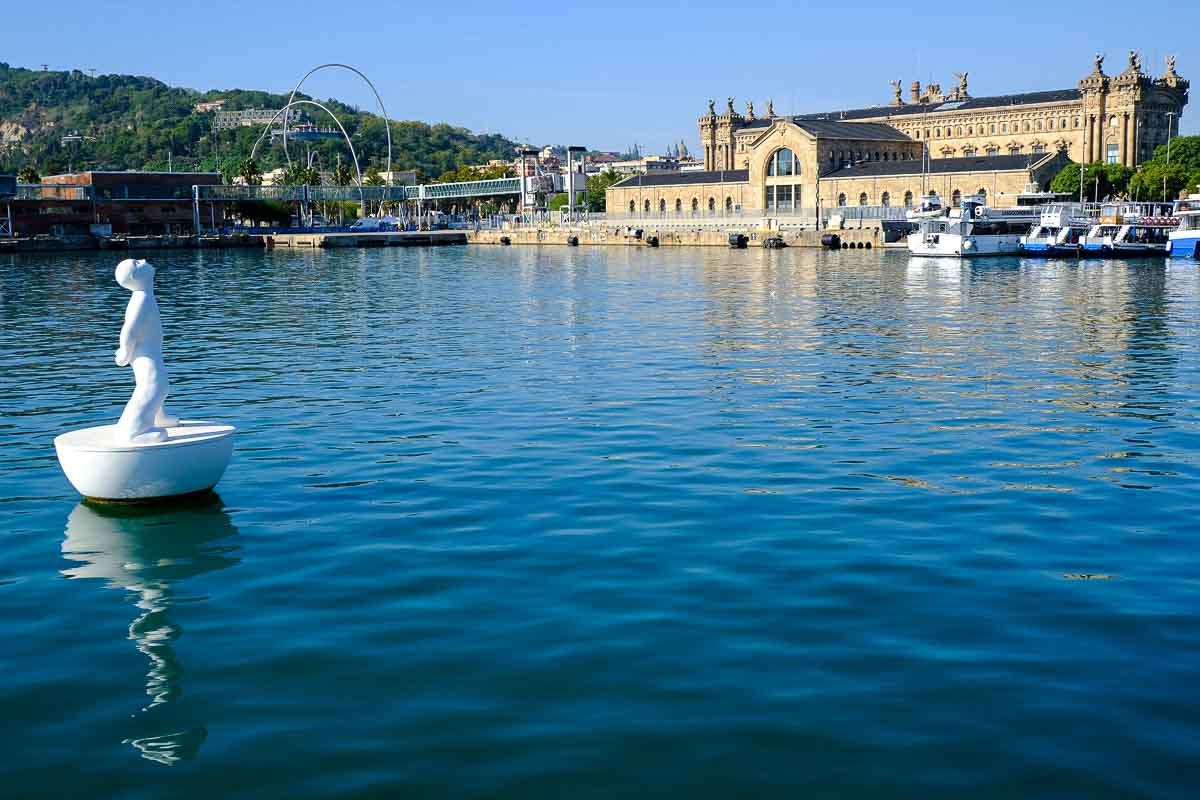 harbour under clear blue sky with white sculpture in water