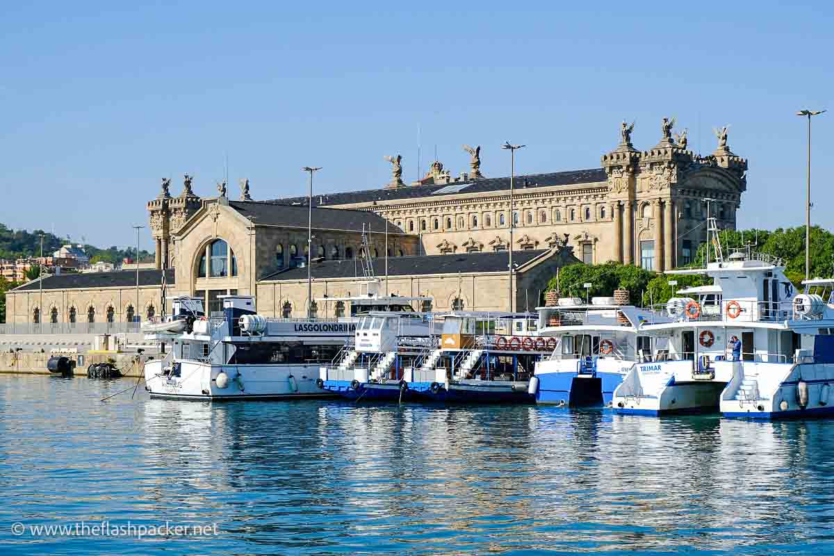 boats lined up in harbour with grand customs building behind them