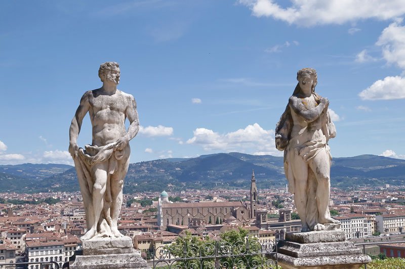 two statues on a terrace with a panoramic view of Florence behind