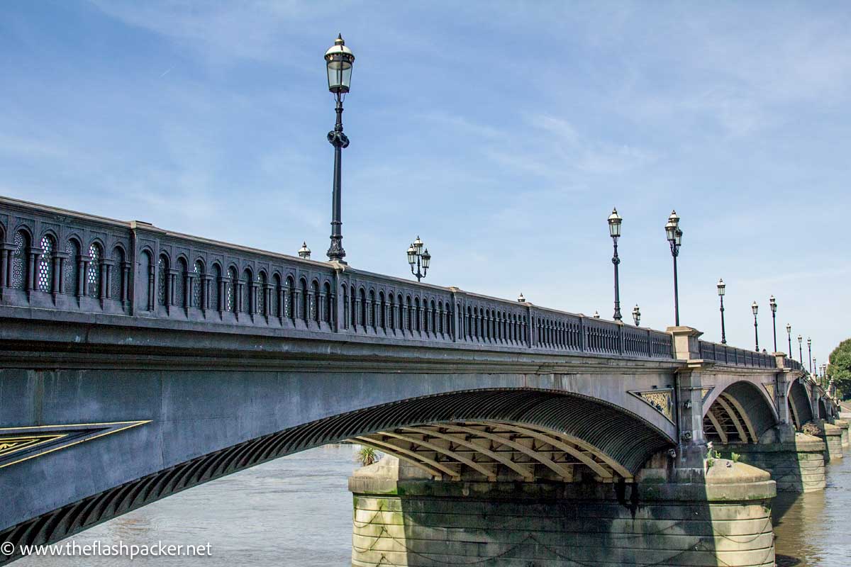 concrete bridge with lamp posts over river thames