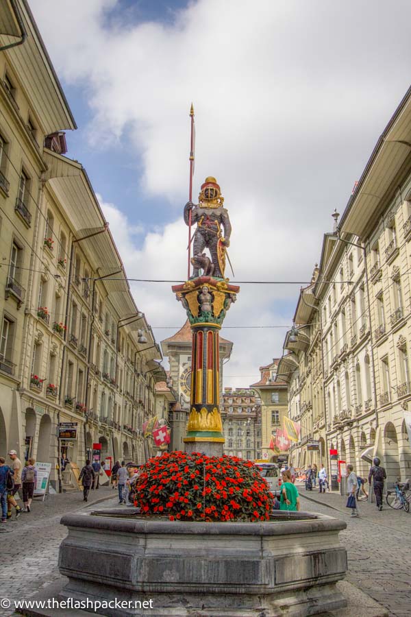 main street in the old town of bern with fountain and red flower in centre