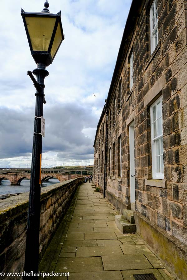 narrow walkway and lamp post by the side of a river in berwick upon tweed