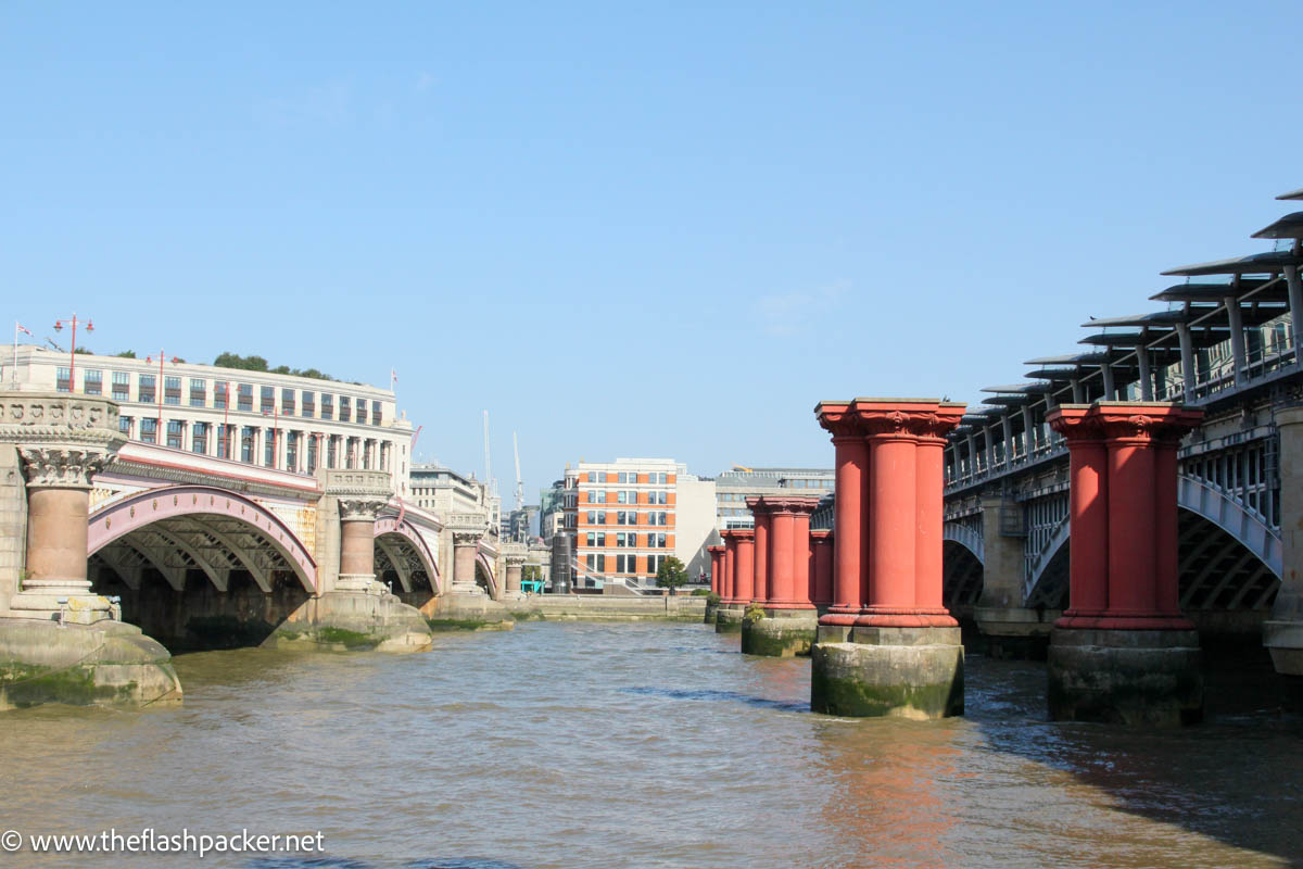 red columns of old bridge between two river bridges in london