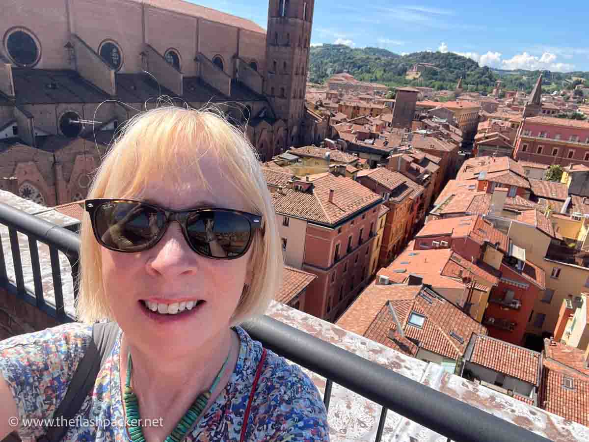 a women standing on a parapet overlooking the red rooftops of bologna