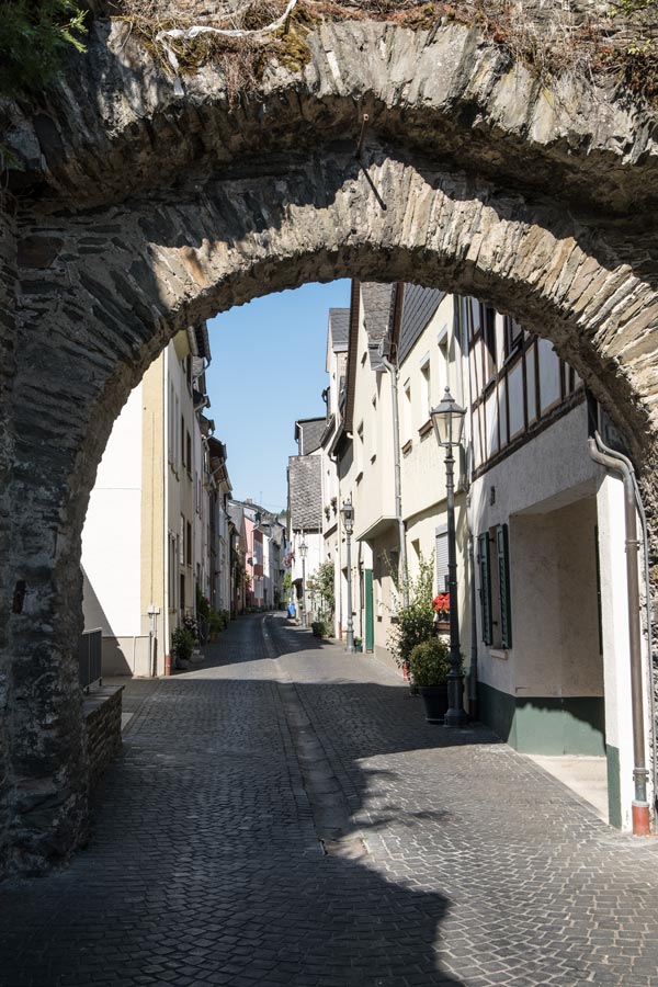 ancient stone gate at the top of a pretty cobbled street with medieval buildings in boppard germany