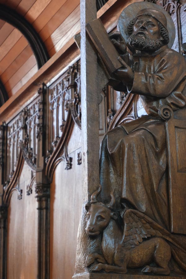 carved wooden sculpture of a saint with a prayer book