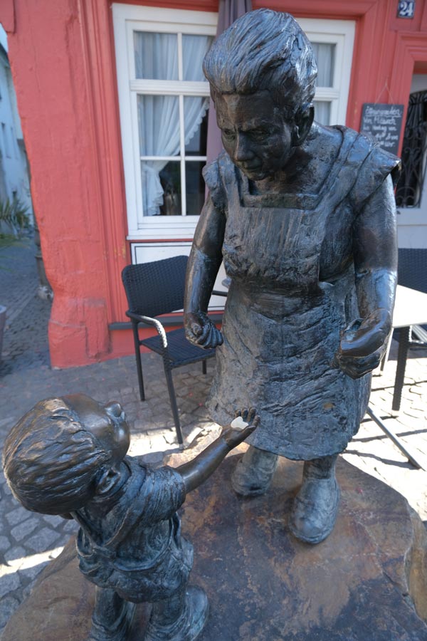 bronze sculpture of child holding his hand out to an old woman