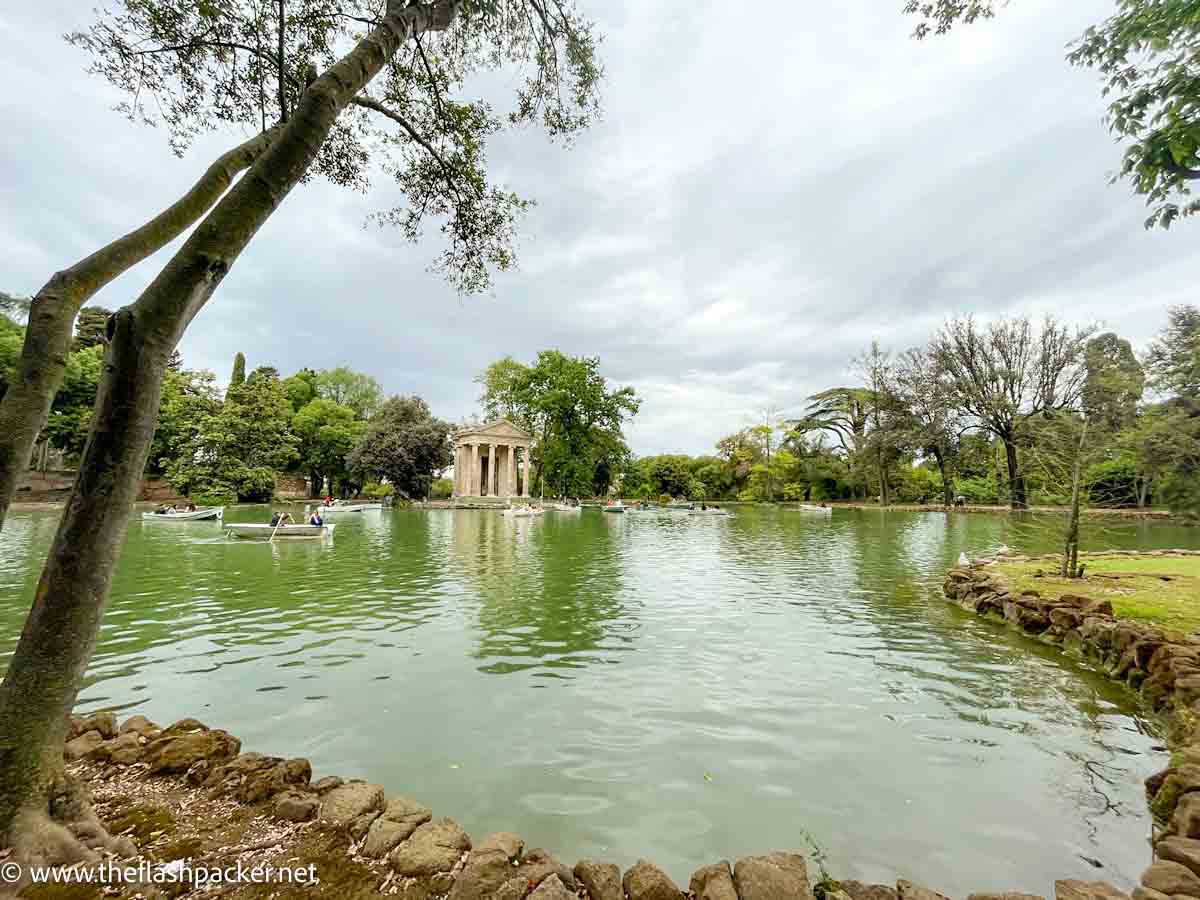 small boating lake with a small temple on an island framed by a large tree