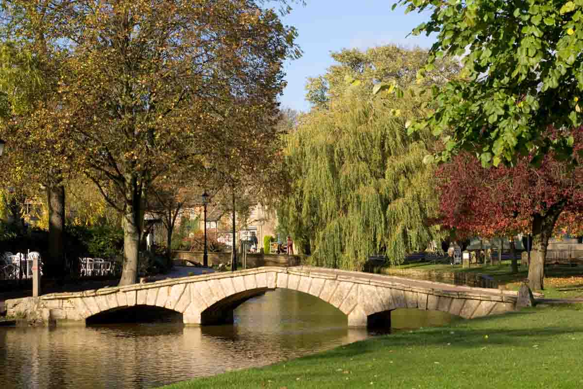 people walking by river in a pretty town in england